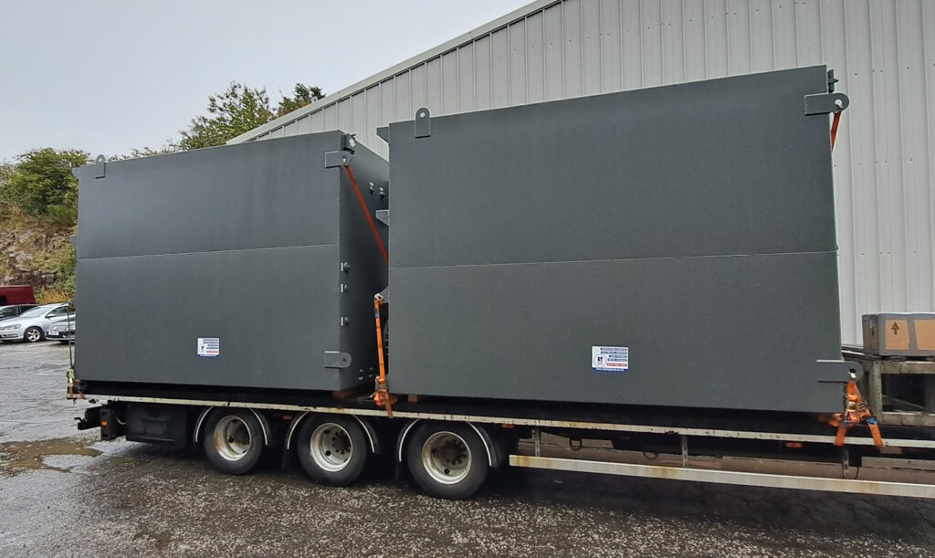 Totally Enclosed Bunded tanks by Blake Group. 2 gray tanks on low loader being transported to Norway for a client